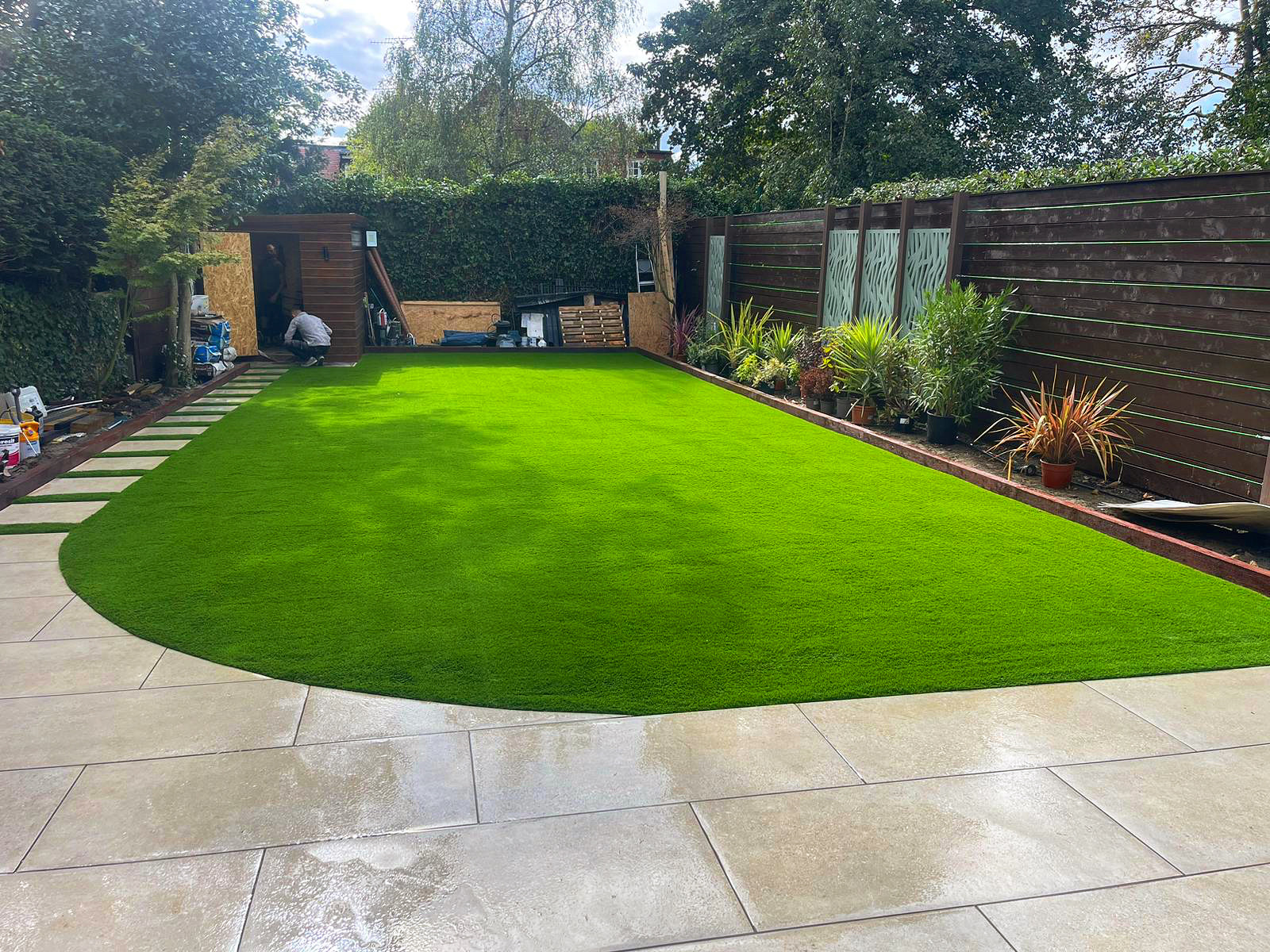 Curved lawn with patio and planting in Finchley